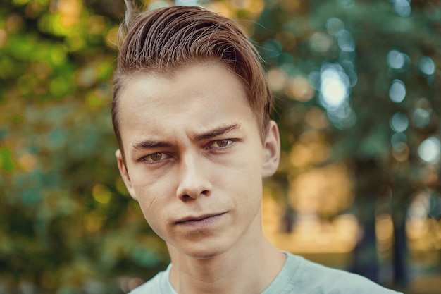 Portret van ernstige jonge aantrekkelijke blanke man 23 jaar oud tijdens een wandeling in het openbaar park.