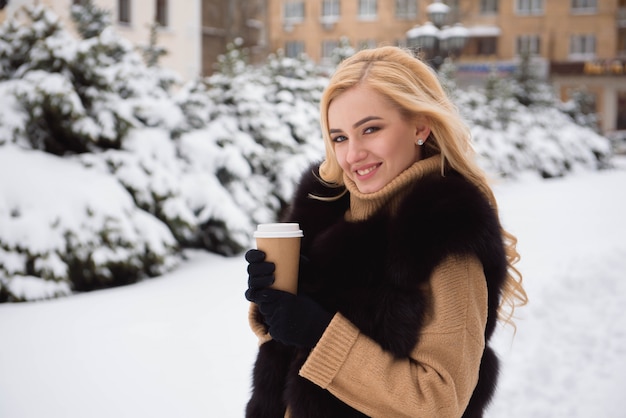 Portret van Europese stijl modieuze vrouw het drinken koffie in de winterpark.