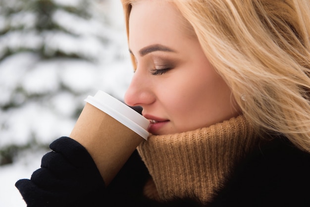 Portret van Europese stijl modieuze vrouw het drinken koffie in de winterpark.