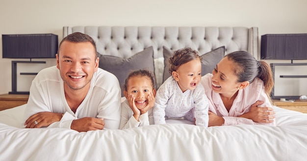 Portret van familie in huis slaapkamer jonge kinderen glimlachen op bed en moeder lachen met meisje baby geluk Gezicht van gelukkige vader ochtend knuffelen samen en grappige mama ontspannen in pyjama's op weekendrust