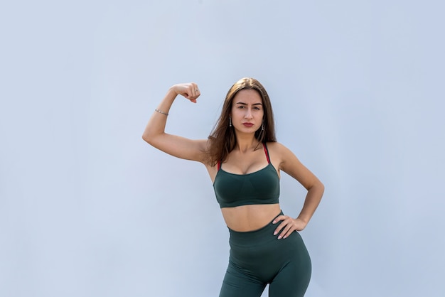 Portret van fitness vrouw in sportkleding poseren geïsoleerd op grijze muur. gezondheid en sport concept