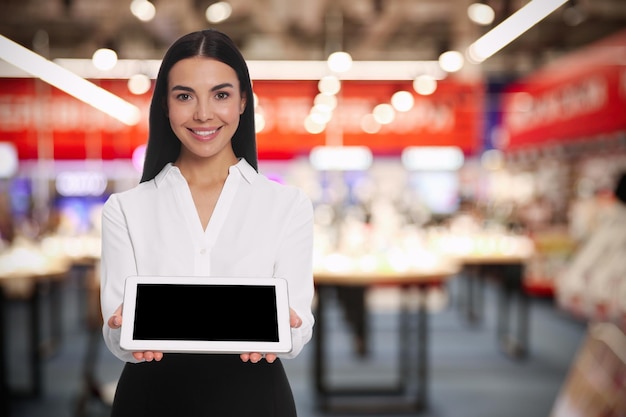 Portret van gastvrouw in uniform met tablet in winkelcentrum Ruimte voor tekst