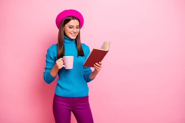 Portret van gefocust vrolijk meisje hebben weekends gelezen leerboek houden warme drank mok draag paarse broek.