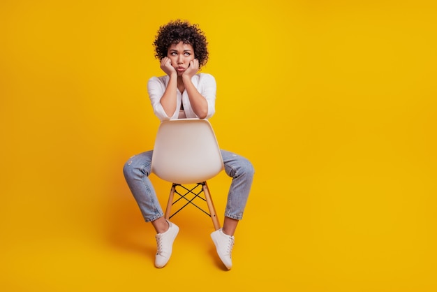 Portret van gefrustreerde vrouw huilend zit stoel slecht humeur op gele muur