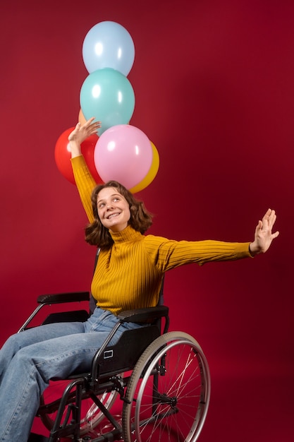 Foto portret van gehandicapte vrouw in een rolstoel met ballonnen