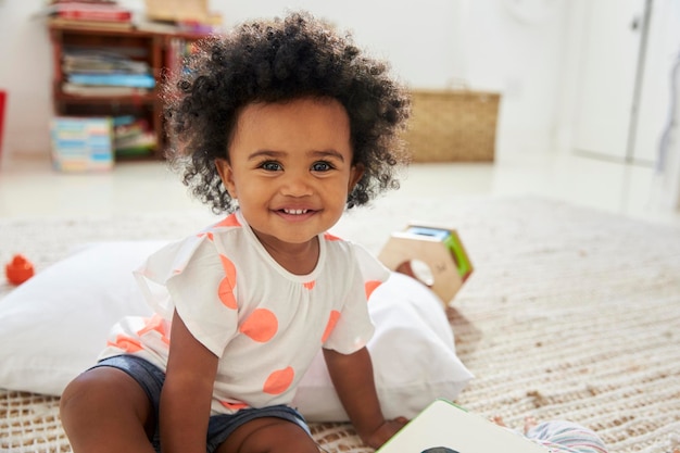 Portret van gelukkig babymeisje dat met speelgoed in speelkamer speelt