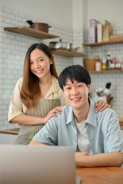 Portret van gelukkig en lachend jong Aziatisch stel aan eettafel in de keuken gelukkige familie