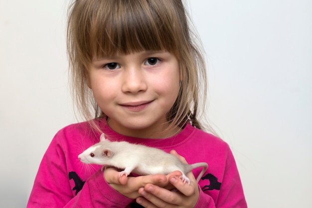 Portret van gelukkig glimlachend leuk kindmeisje met de witte hamster van de huisdierenmuis