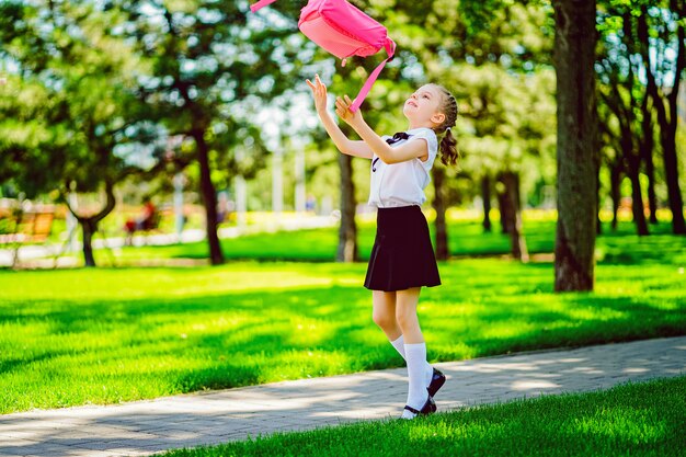 Portret van gelukkig jong glimlachend meisje die schoolrugzak buiten de lage school dragen