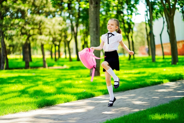 Portret van gelukkig jong glimlachend meisje die schoolrugzak buiten de lage school dragen