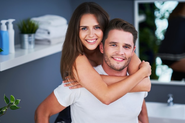 Portret van gelukkig jong stel knuffelend in de badkamer