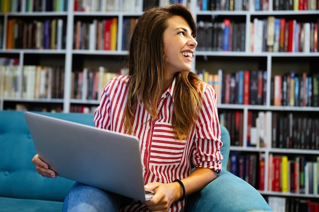 Portret van gelukkig jong studentenmeisje dat aan laptop werkt