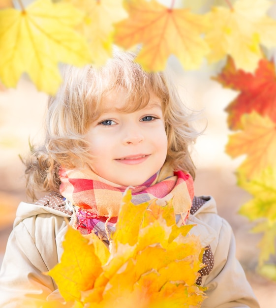 Portret van gelukkig kind in de herfst. Frame van gouden esdoornbladeren