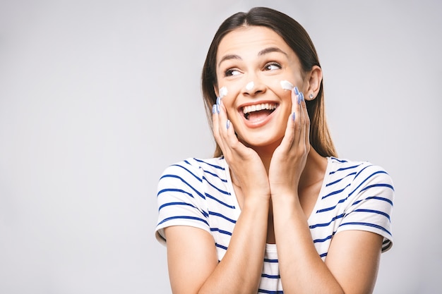 Portret van gelukkig lachend mooie jonge vrouw huid aan te raken of crème toe te passen