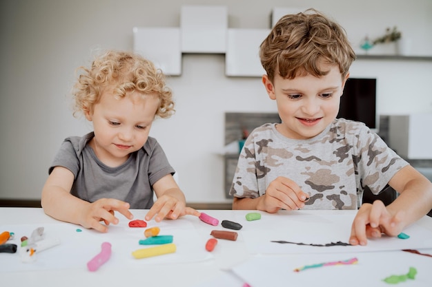 Portret van gelukkig lachende broers en zussen die aan de keukentafel zitten en samen genieten van hun vrije tijd