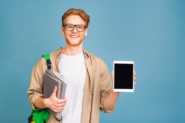 portret van gelukkig lachende jonge student permanent met rugzak en mappen. tablet gebruiken