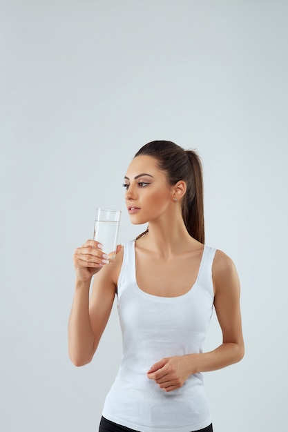 Portret van gelukkig lachende jonge vrouw met een glas vers water. Gezondheidszorg. Drankjes.