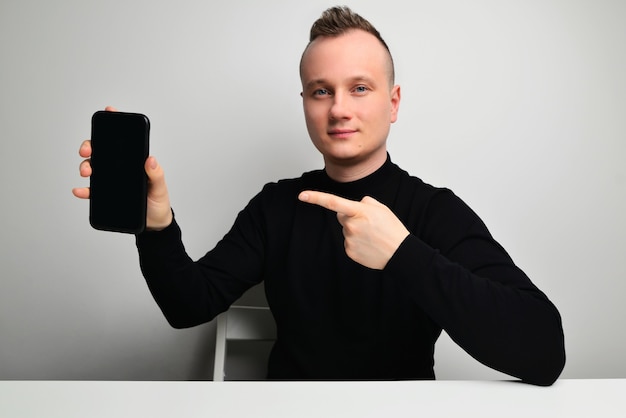 Portret van gelukkig mannetje geïsoleerd op een grijze achtergrond met een smartphone