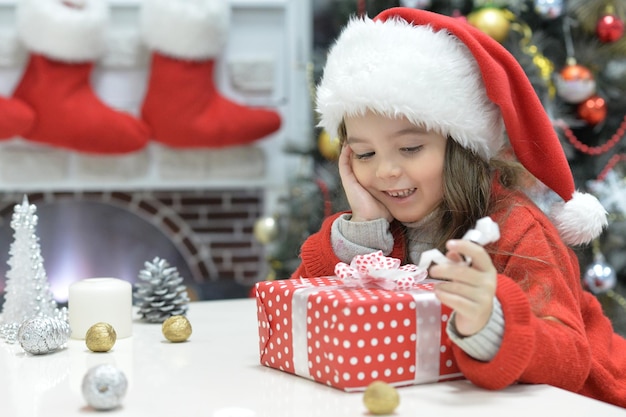 Portret van gelukkig meisje in kerstmuts zittend met kerstcadeau