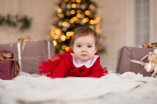 Portret van gelukkig meisje in rode gebreide trui met kerstcadeautje in de buurt van de kerstboom