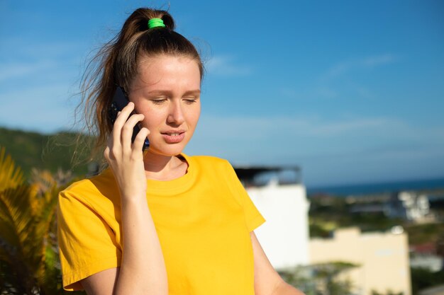 Portret van gelukkig mooi meisje jonge positieve vrouw praat op haar mobiele telefoon bellen op smartphone op zonnige zomerdag op hemelachtergrond genieten van gesprek met vriend