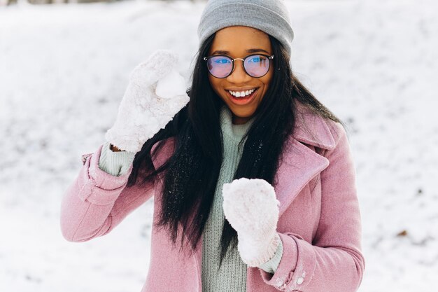 Portret van gelukkig positief meisje Afrikaanse jonge vrouw in glazen en handschoenen lacht in de winter