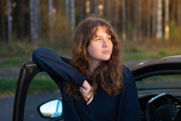 Portret van gelukkig positief meisje jonge vrouw bestuurder zit in haar auto nieuwe auto genieten van rijden plezier lachen Blije dame in auto kijken naar camera staande in de buurt van auto met sleutels