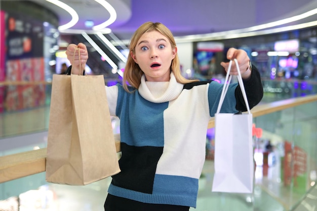 Portret van gelukkig positief stijlvol meisje jonge tiener tiener mooie vrouw lacht plezier in winkelcentrum tijdens het winkelen met papieren zakken in de hand houden