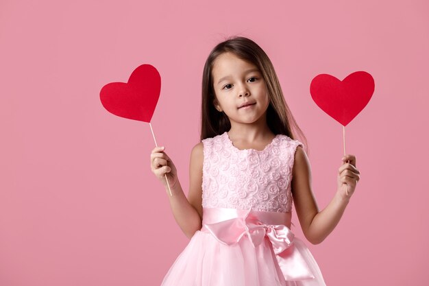 Portret van gelukkig schattig klein kind meisje in een roze jurk met papier hart