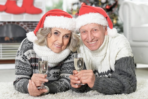 Portret van gelukkig senior paar in kerstmutsen met champagne