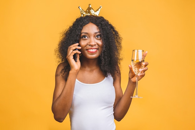 Portret van gelukkige Afro-Amerikaanse zwarte vrouw met glas champagne en gouden kroon
