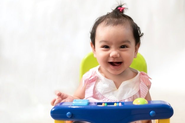 Portret van gelukkige Aziatische baby zittend op de eettafel, glimlachend vrolijk kijken naar de camera