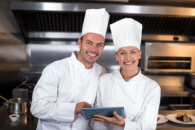 Portret van gelukkige chef-koks die klembord in keuken houden