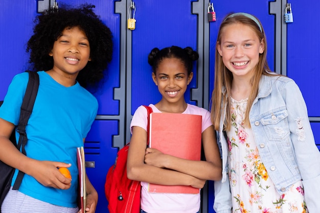 Foto portret van gelukkige diverse schoolkinderen die naast kastjes in de gang van de school staan