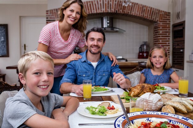 Portret van gelukkige familie die maaltijd in keuken heeft