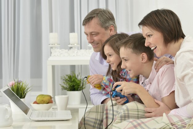 Portret van gelukkige familie die thuis op laptop speelt