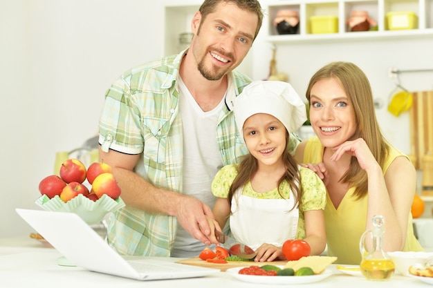 portret van gelukkige familie koken in de keuken met laptop