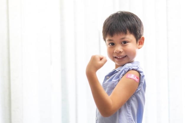 Portret van gelukkige glimlach gevaccineerde kleine Aziatische jongen jongen kinderen van 5 tot 11 jaar oud poseren show arm met medische pleister na injectie vaccin Covid19 beschermingcoronavirus vaccinatie kind