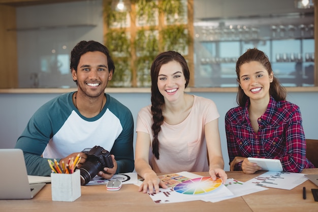 Portret van gelukkige grafische ontwerpers die aan bureau zitten