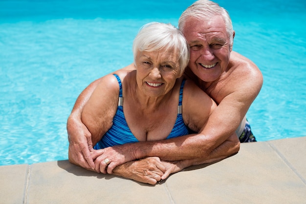 Portret van gelukkige hogere paar die elkaar in pool omhelzen