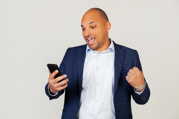 Portret van gelukkige jonge Afro-Amerikaanse zakenman man met behulp van slimme telefoon, schreeuwen van trots en vieren overwinning en succes, erg opgewonden, vreugde emoties.