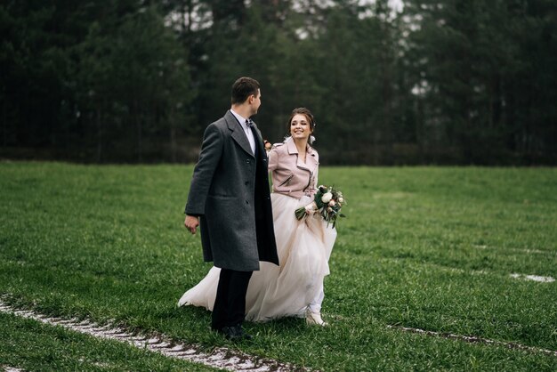 Portret van gelukkige jonge liefdevolle jonggehuwden. de bruid en bruidegom rennen over het veld met de eerste sneeuw. trouwdag