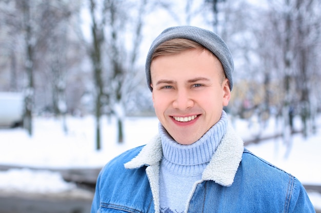 Portret van gelukkige jonge man in besneeuwde park op wintervakantie