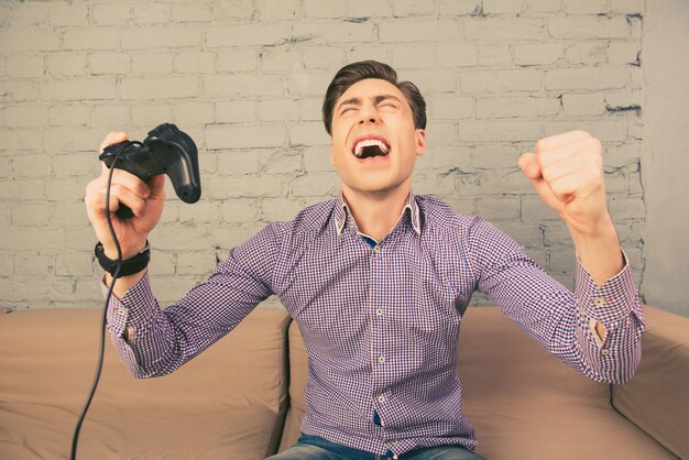 Portret van gelukkige jonge man schreeuwen en joystick te houden