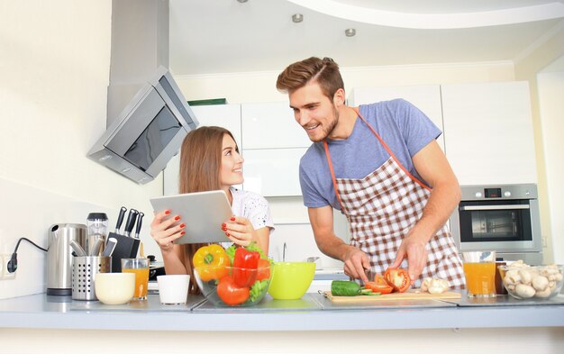 Portret van gelukkige jonge paar samen koken in de keuken thuis.