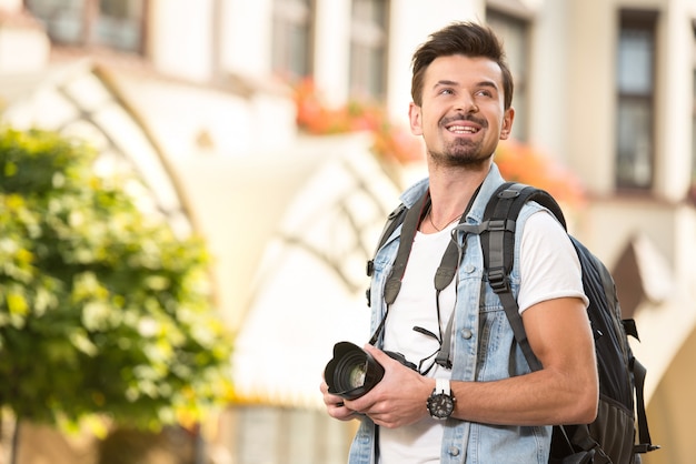 Portret van gelukkige jonge toerist met camera in stad.