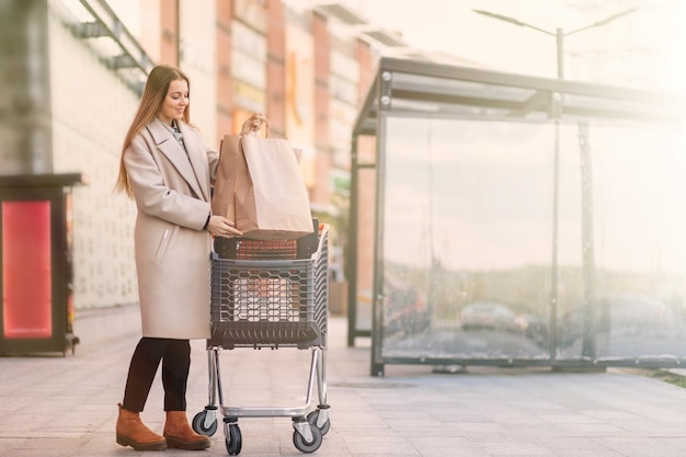 Portret van gelukkige jonge vrouw met boodschappentassen op de steeg van het winkelcentrum