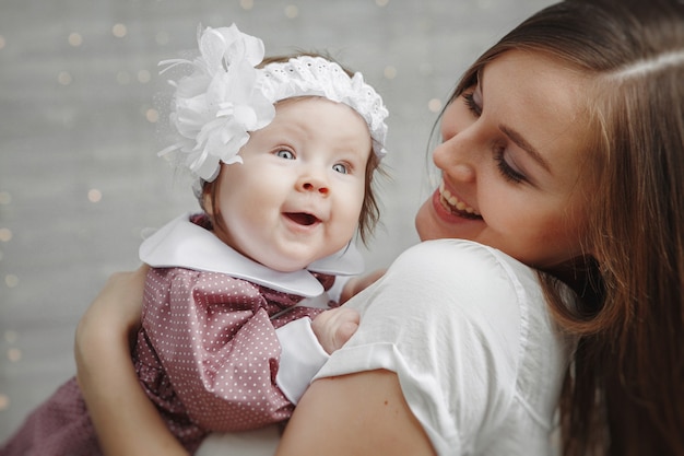 Portret van gelukkige jonge vrouw met schattige baby op lichte achtergrond