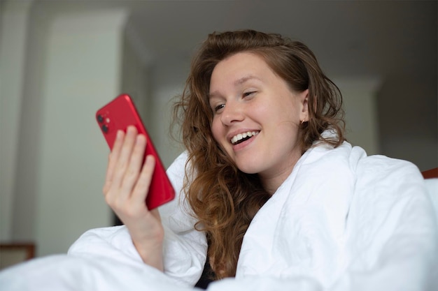 Portret van gelukkige jonge vrouw positief vrolijk blij meisje kijkt naar het scherm van haar mobiele telefoon