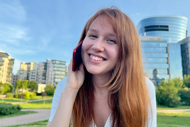 Portret van gelukkige jonge vrouw praten op mobiele telefoon bellen op smartphone buitenshuis in de zomer